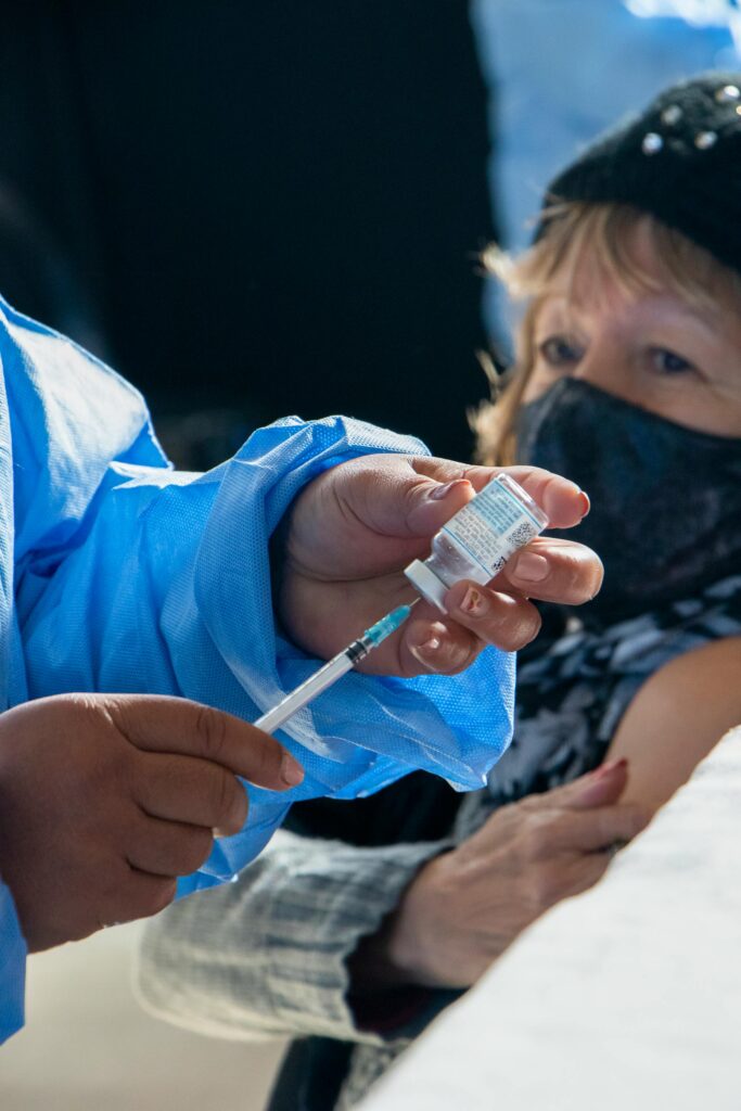 Healthcare professional preparing a vaccine dose for a patient during a vaccination drive.